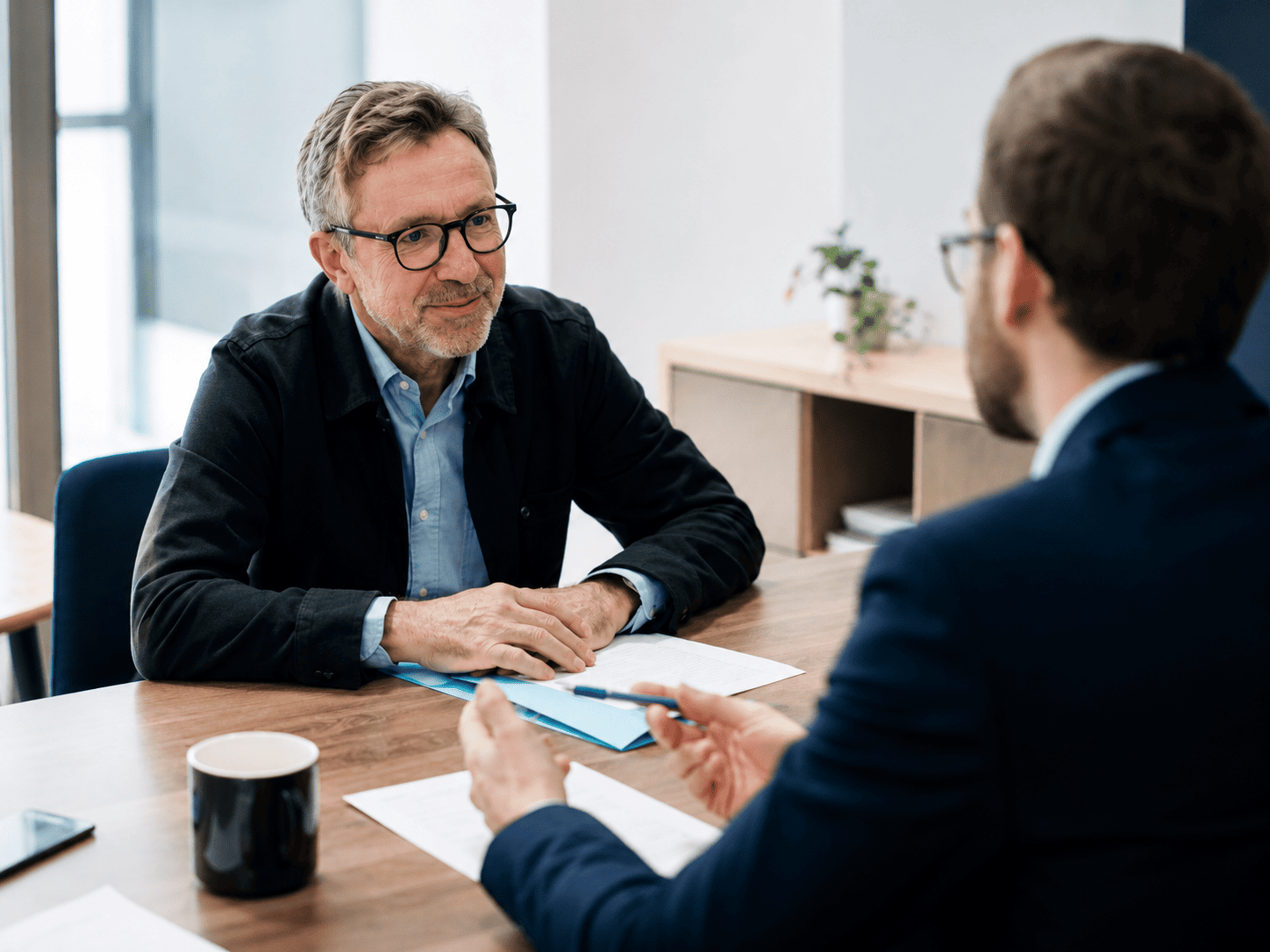 Homme senior en rendez-vous avec un conseiller retraite, échange autour de documents administratifs pour préparer sa demande de départ à la retraite